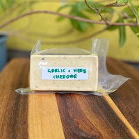 Block of vegan garlic and herb cheddar in its wrapper